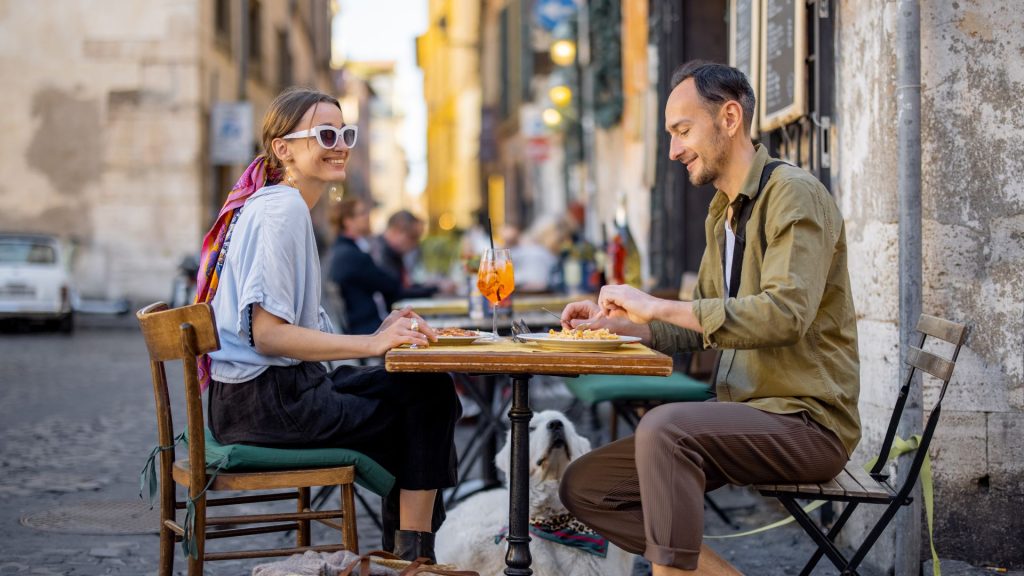 Repas d'un jeune couple à la terrasse d'Alfredo e Ada, dans un cadre typique de Rome. Des sourires sur les regard de nos jeunes amoureux qui dégustent leurs plats